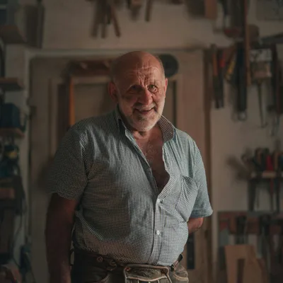 A tradesman standing in a workshop with hand tools hung along the wall